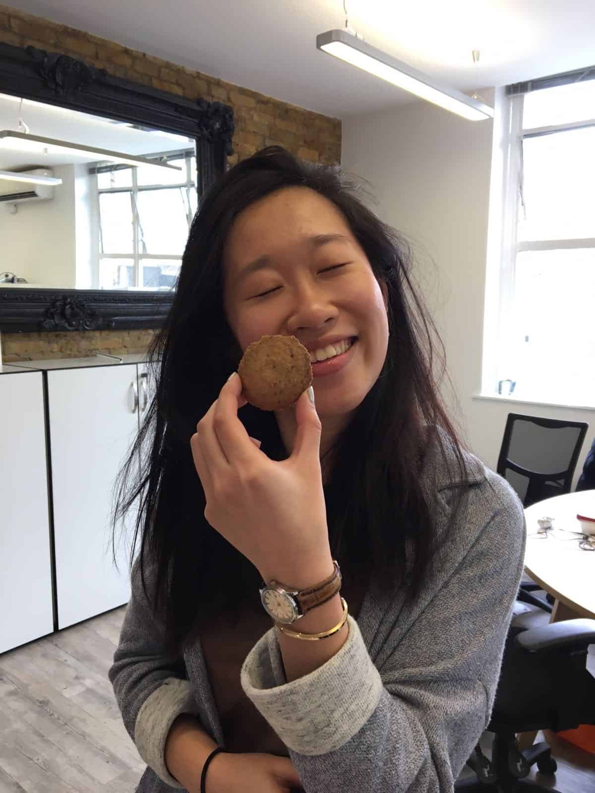 Woman smiling with a cookie held against her face