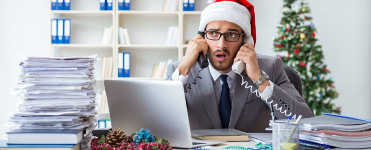Office worker wearing a Christmas hat feeling stressed in run up to holidays