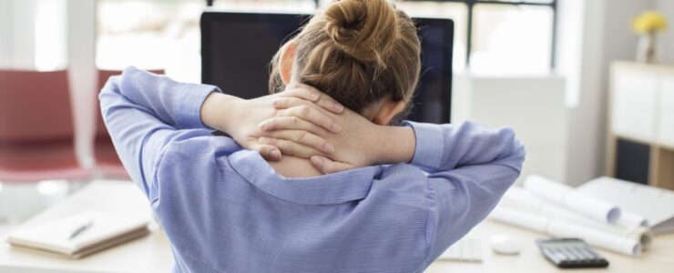 A worker suffering from neck pain sitting at a computer